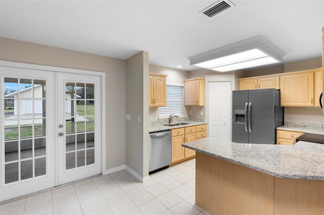 kitchen with stainless steel appliances, a sink, and light brown cabinetry