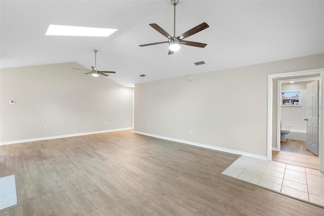 unfurnished room with light wood-style floors, ceiling fan, visible vents, and lofted ceiling with skylight