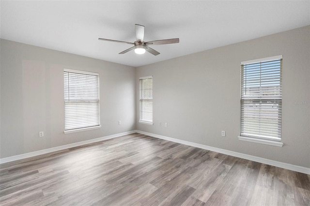 empty room with wood finished floors, a ceiling fan, and baseboards