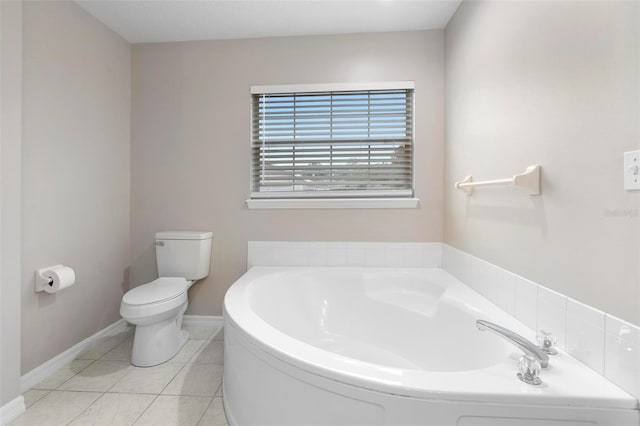 bathroom with a bath, baseboards, toilet, and tile patterned floors