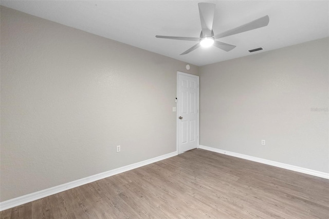 unfurnished room with baseboards, visible vents, ceiling fan, and wood finished floors