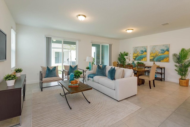 living room featuring light tile patterned floors, visible vents, and baseboards