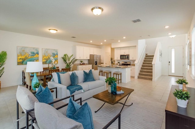 living room featuring light tile patterned floors, recessed lighting, visible vents, baseboards, and stairs