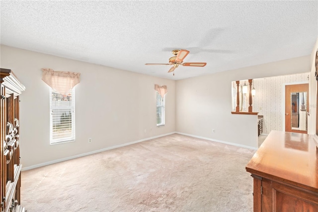 unfurnished room featuring a ceiling fan, light colored carpet, a textured ceiling, and baseboards