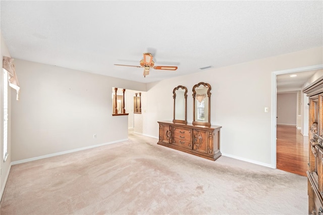 carpeted empty room with visible vents, ceiling fan, and baseboards