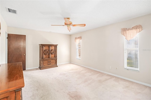 unfurnished room with light carpet, baseboards, and a textured ceiling