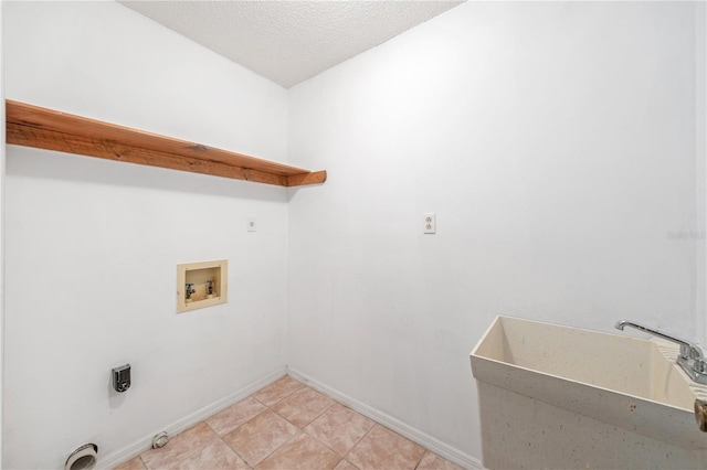 laundry area with hookup for a washing machine, a sink, a textured ceiling, laundry area, and baseboards