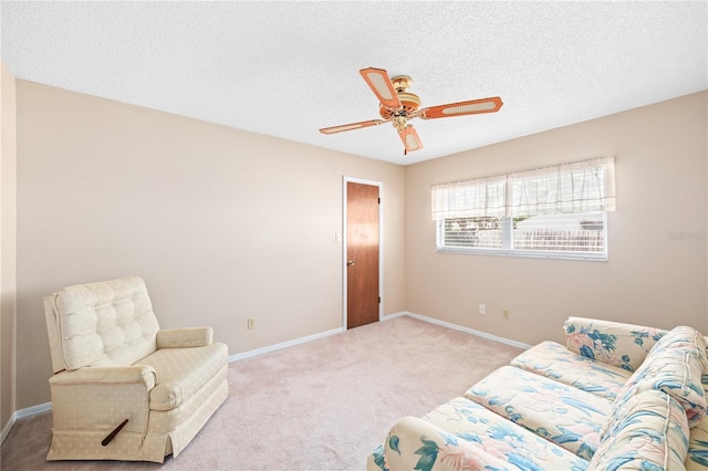 living area featuring carpet, ceiling fan, a textured ceiling, and baseboards