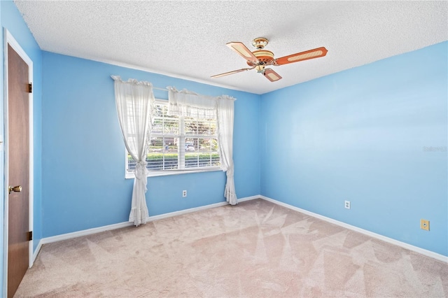 carpeted spare room with ceiling fan, a textured ceiling, and baseboards