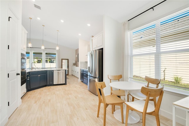 kitchen with visible vents, light wood finished floors, stainless steel appliances, light countertops, and vaulted ceiling