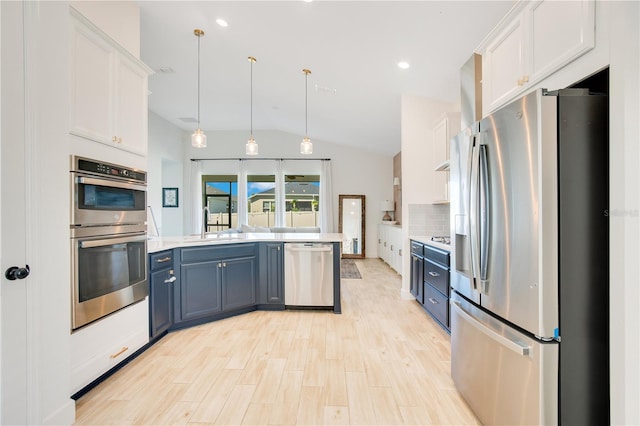 kitchen featuring backsplash, light countertops, a peninsula, white cabinets, and stainless steel appliances