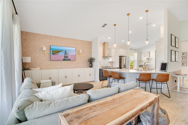 living area featuring light wood finished floors, visible vents, wallpapered walls, baseboards, and recessed lighting