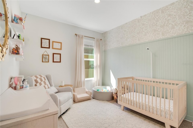 bedroom with wainscoting, wallpapered walls, and a crib