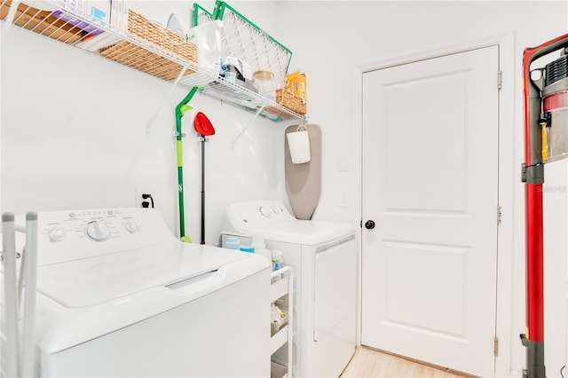 clothes washing area with light wood-type flooring, laundry area, and washer and clothes dryer