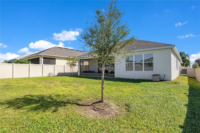 rear view of property with central AC unit, stucco siding, a lawn, and a fenced backyard