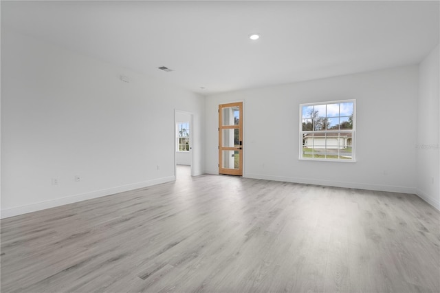 empty room with light wood-style flooring, visible vents, and baseboards