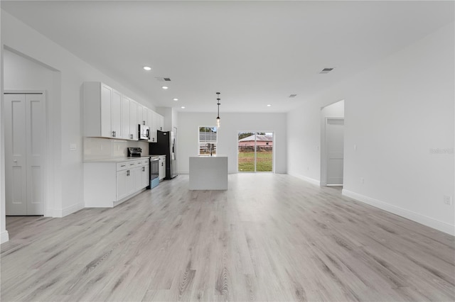 unfurnished living room featuring baseboards, visible vents, and light wood-style floors