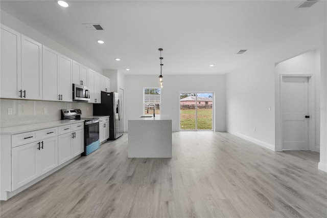 kitchen with tasteful backsplash, light wood-style flooring, appliances with stainless steel finishes, white cabinetry, and a sink