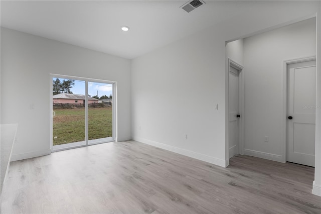 spare room featuring light wood-type flooring, visible vents, and baseboards