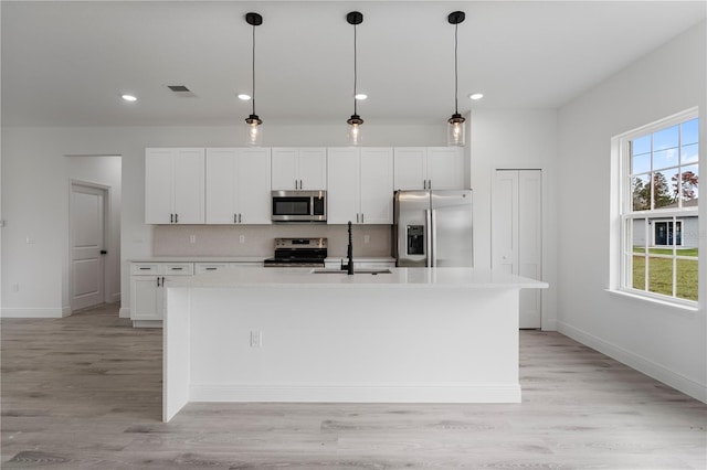 kitchen featuring a center island with sink, visible vents, backsplash, appliances with stainless steel finishes, and a sink