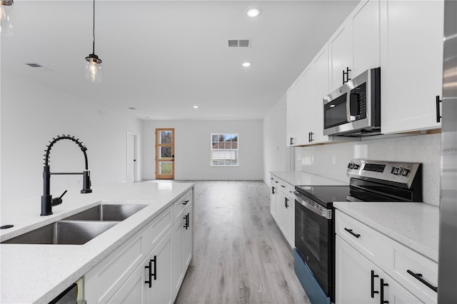 kitchen featuring visible vents, decorative backsplash, appliances with stainless steel finishes, pendant lighting, and a sink