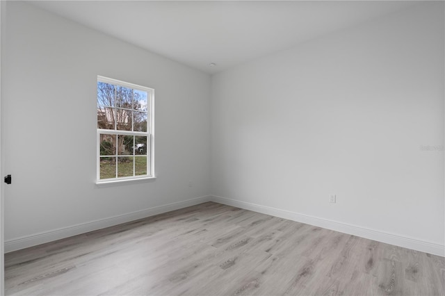 spare room featuring light wood finished floors and baseboards