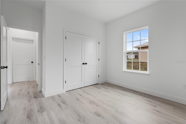 unfurnished bedroom featuring a closet, baseboards, and wood finished floors