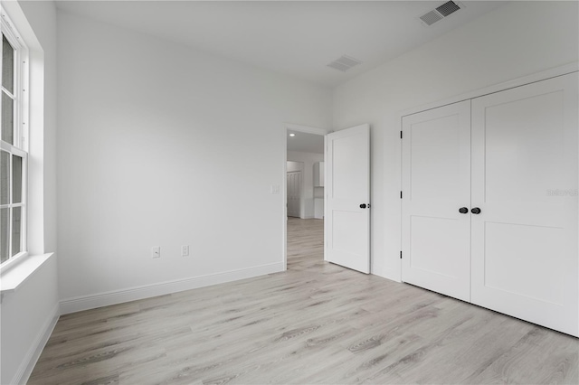 unfurnished bedroom with light wood finished floors, a closet, visible vents, and baseboards