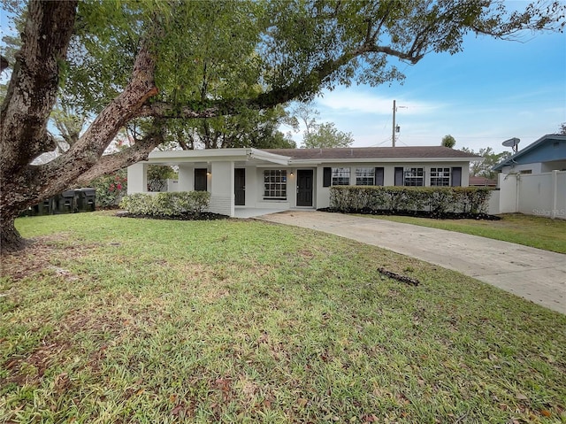 ranch-style home featuring driveway, a front yard, fence, and stucco siding