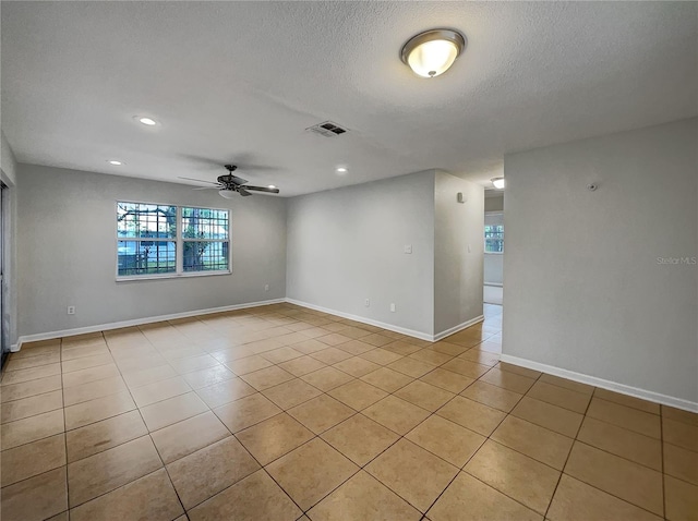 empty room featuring visible vents, a textured ceiling, baseboards, and light tile patterned flooring