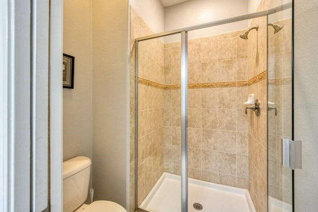 full bathroom featuring toilet and a shower stall