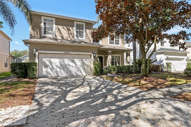 traditional-style house with concrete driveway, an attached garage, and stucco siding