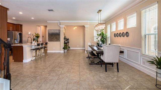 dining room featuring decorative columns, visible vents, crown molding, a decorative wall, and recessed lighting