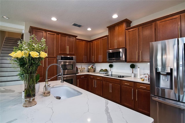 kitchen with light stone counters, tasteful backsplash, visible vents, appliances with stainless steel finishes, and a sink