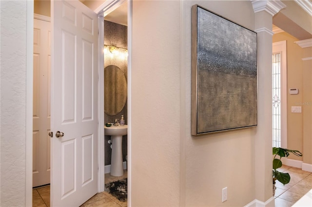 hallway featuring light tile patterned floors, a sink, and baseboards