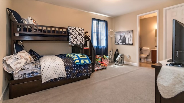 bedroom with ensuite bathroom, carpet floors, and baseboards