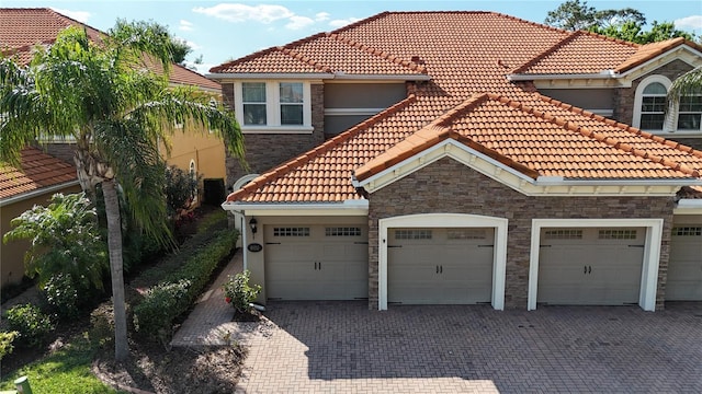 mediterranean / spanish home with a garage and decorative driveway