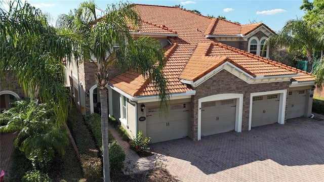 view of front facade featuring decorative driveway, stone siding, and a tile roof