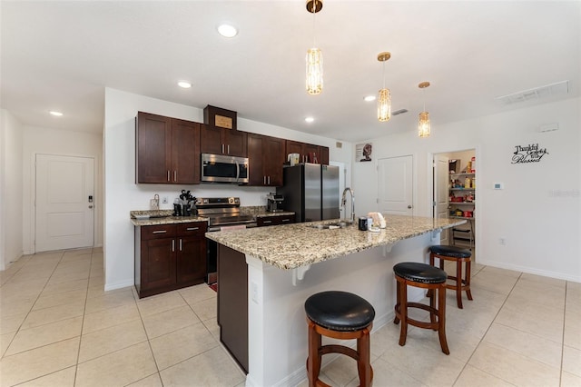 kitchen featuring appliances with stainless steel finishes, light tile patterned flooring, a kitchen bar, and pendant lighting