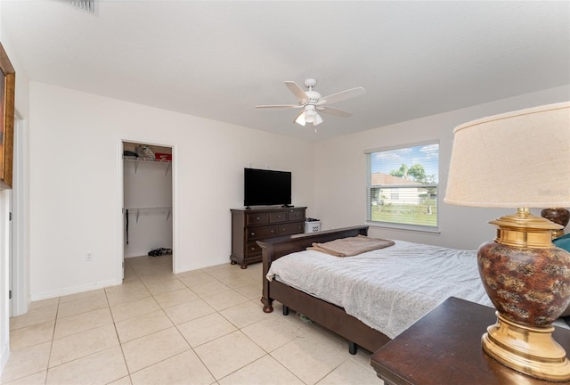 bedroom with ceiling fan, light tile patterned flooring, baseboards, a closet, and a walk in closet