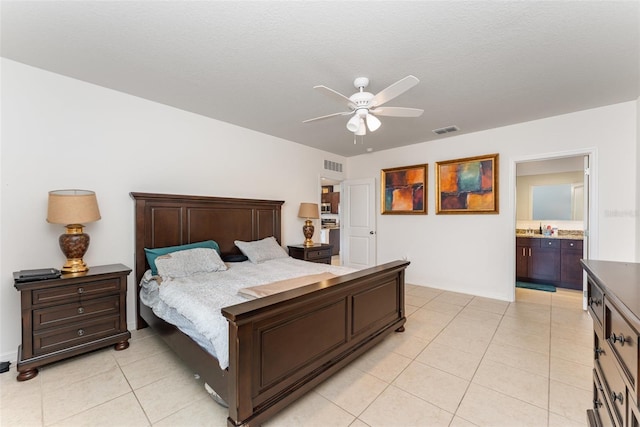 bedroom featuring a ceiling fan, visible vents, connected bathroom, and light tile patterned floors