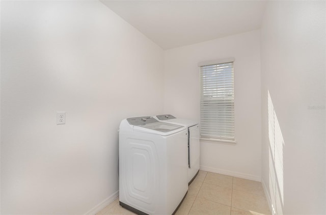 clothes washing area featuring washer and dryer, laundry area, baseboards, and light tile patterned floors