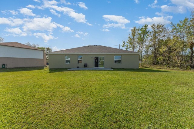 rear view of property with a yard, a patio area, and stucco siding