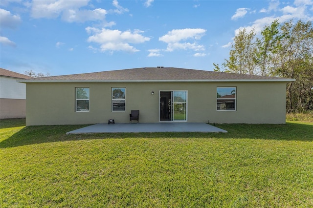 rear view of property featuring a lawn, a patio area, and stucco siding