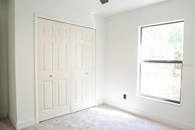 unfurnished bedroom with carpet floors, a closet, and baseboards