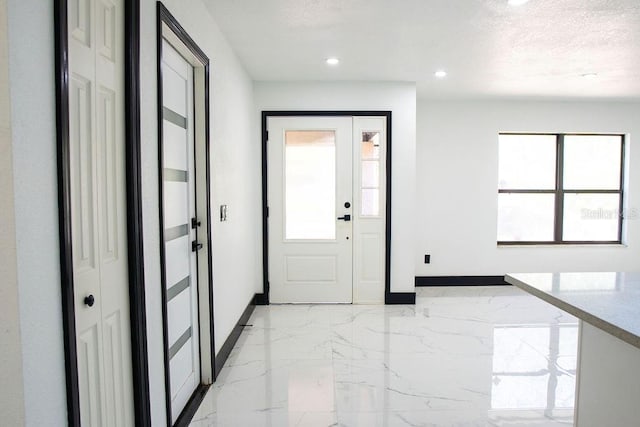 entryway with marble finish floor, baseboards, a textured ceiling, and recessed lighting