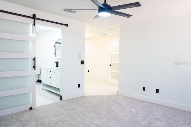 unfurnished bedroom featuring marble finish floor, visible vents, a barn door, carpet flooring, and baseboards