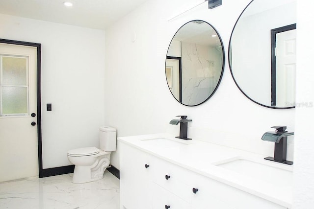 bathroom featuring marble finish floor, a sink, toilet, and double vanity