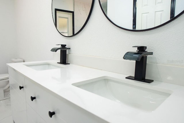 full bath with a sink, toilet, and double vanity