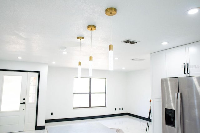 kitchen featuring marble finish floor, stainless steel refrigerator with ice dispenser, recessed lighting, hanging light fixtures, and white cabinetry